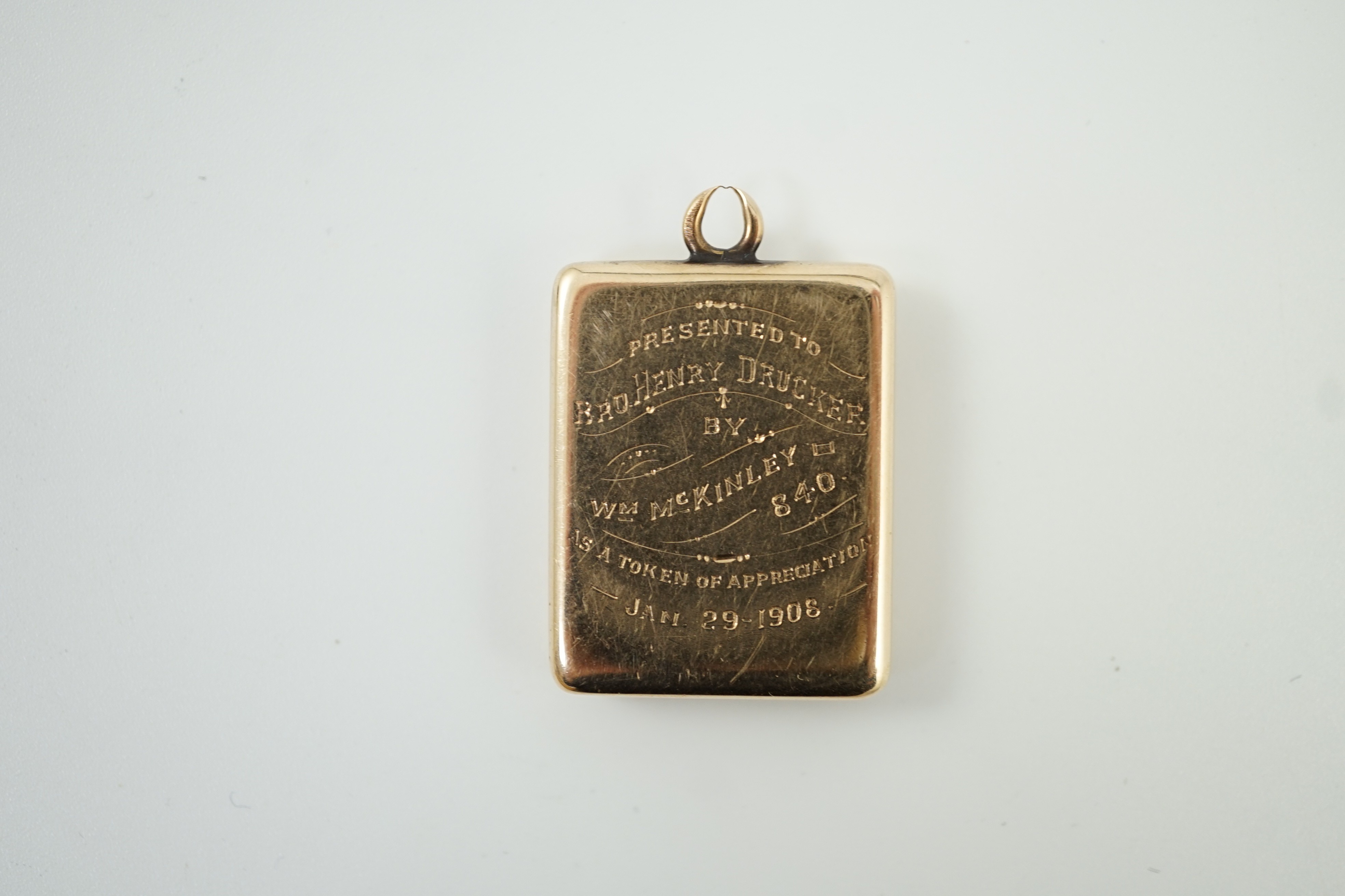 An Edwardian yellow metal and diamond cluster set masonic locket pendant, with engraved inscription verso 'Presented to Henry Drucker by Wm. McKinley', overall 33mm, gross weight 12.3 grams.